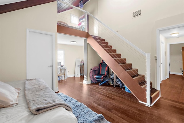 stairs with baseboards, a towering ceiling, wood finished floors, and visible vents