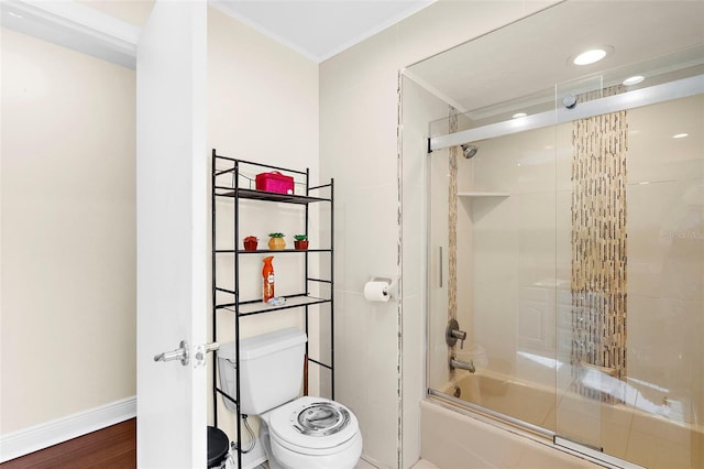 bathroom featuring shower / bath combination with glass door, toilet, baseboards, wood finished floors, and ornamental molding