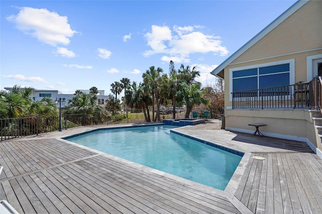 view of pool with a wooden deck, fence, and a pool with connected hot tub