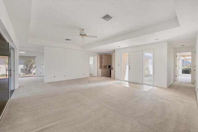 carpeted empty room featuring a textured ceiling, a tray ceiling, and ceiling fan