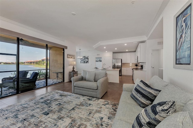 tiled living room featuring a water view, ornamental molding, and sink