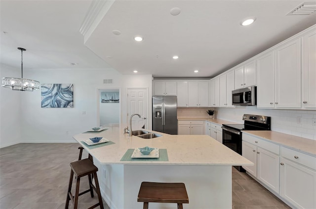 kitchen with appliances with stainless steel finishes, sink, decorative light fixtures, and a kitchen island with sink