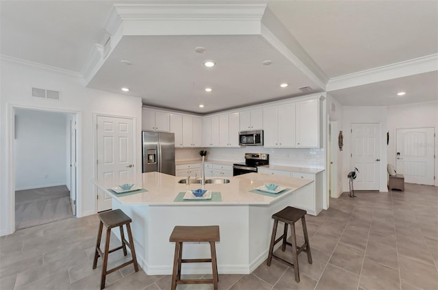 kitchen with a spacious island, sink, a breakfast bar, white cabinetry, and appliances with stainless steel finishes