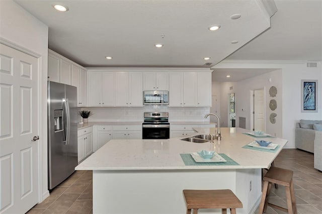 kitchen featuring sink, appliances with stainless steel finishes, a kitchen island with sink, and a breakfast bar