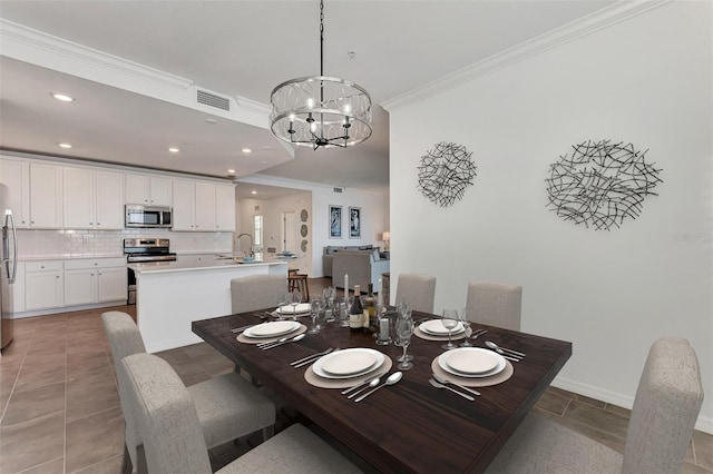 dining room with crown molding, a notable chandelier, sink, and tile patterned flooring