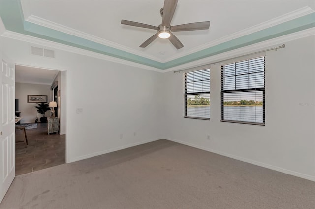 carpeted empty room featuring ornamental molding, a tray ceiling, and ceiling fan