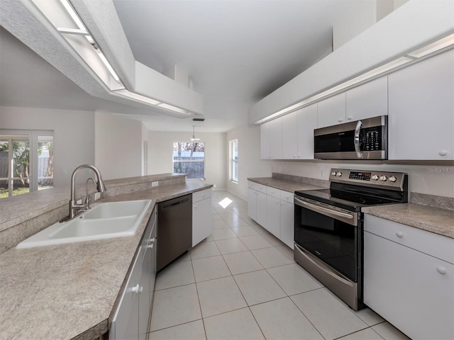 kitchen featuring white cabinets, appliances with stainless steel finishes, plenty of natural light, pendant lighting, and sink