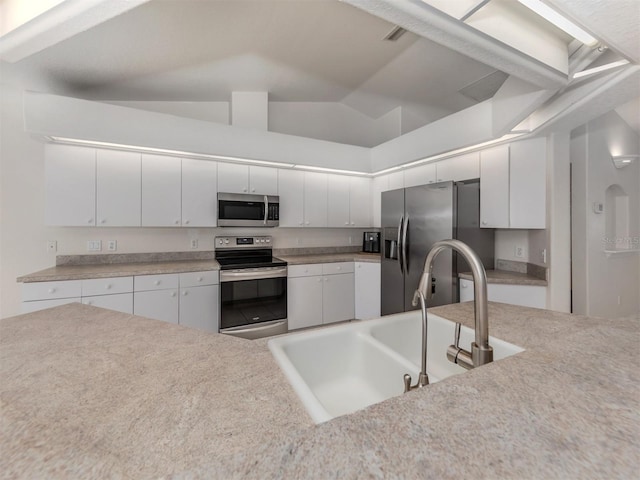 kitchen with white cabinetry, stainless steel appliances, lofted ceiling, and sink