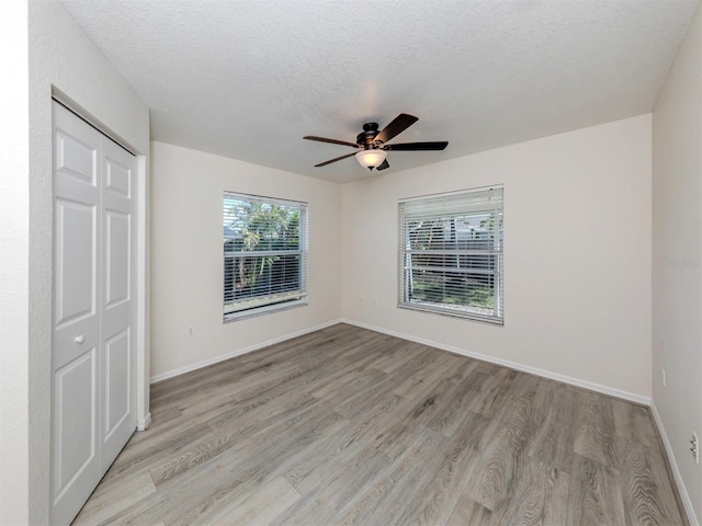 unfurnished bedroom with a closet, ceiling fan, a textured ceiling, and light hardwood / wood-style flooring