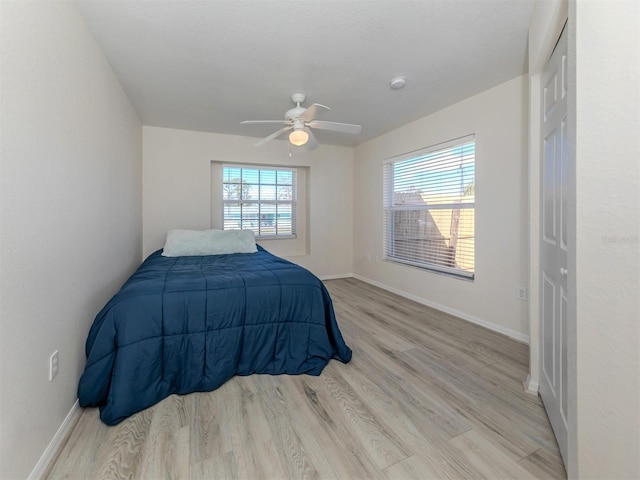 bedroom featuring light hardwood / wood-style flooring, multiple windows, and ceiling fan