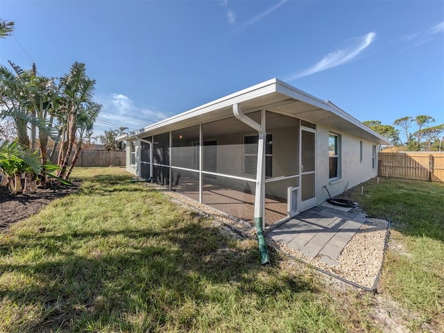 back of property with a sunroom and a lawn