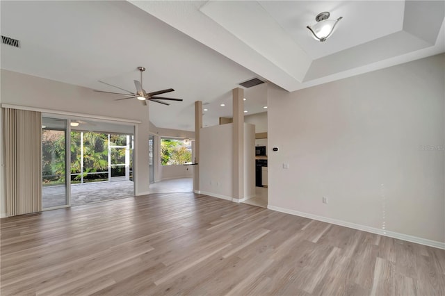 unfurnished living room with light hardwood / wood-style floors, a raised ceiling, and ceiling fan