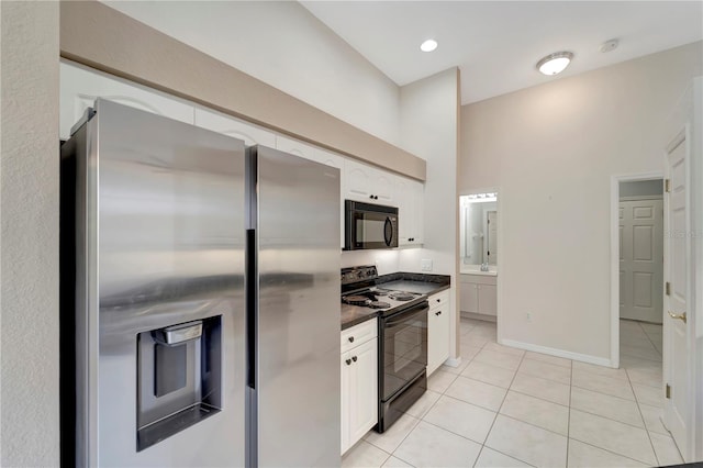 kitchen with white cabinetry, a towering ceiling, light tile patterned floors, and black appliances