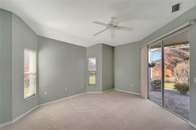 carpeted spare room with a wealth of natural light, lofted ceiling, and ceiling fan