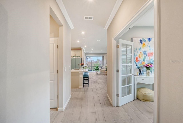 hallway featuring ornamental molding and light wood-type flooring