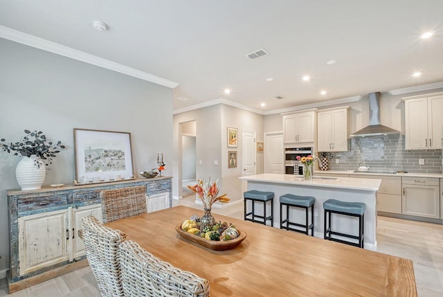 dining room with crown molding, sink, and light hardwood / wood-style floors