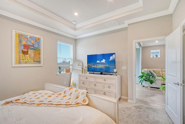 bedroom featuring crown molding, light wood-type flooring, and a raised ceiling