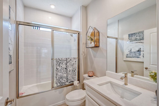 full bathroom featuring toilet, vanity, and shower / bath combination with glass door