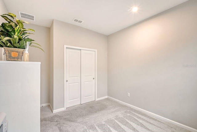 unfurnished bedroom with a closet and light colored carpet