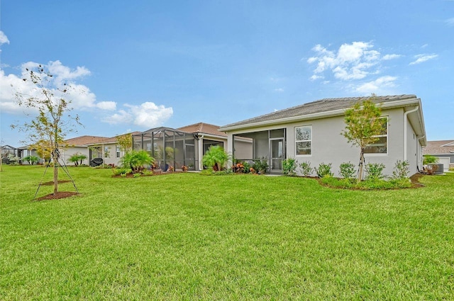 rear view of property featuring a yard and glass enclosure