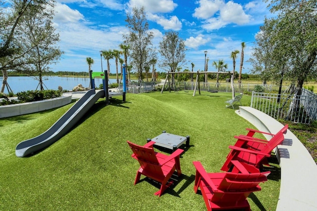 view of home's community with a playground, a yard, and a water view