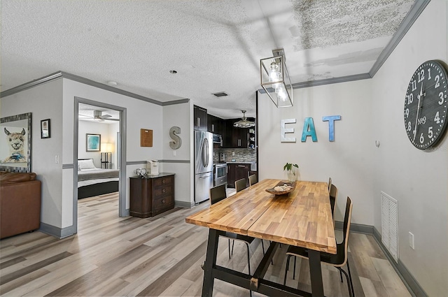 dining room featuring light hardwood / wood-style floors, a textured ceiling, ceiling fan, and ornamental molding