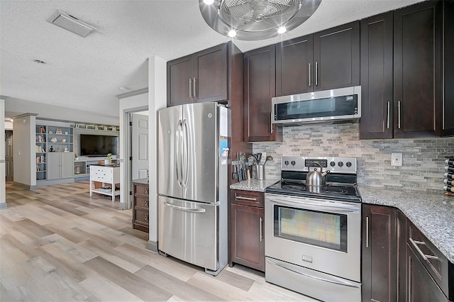 kitchen featuring light stone countertops, a textured ceiling, light hardwood / wood-style floors, stainless steel appliances, and decorative backsplash