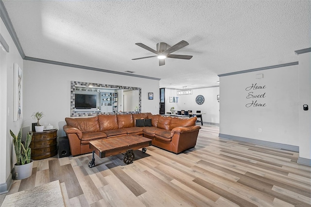 living room featuring light hardwood / wood-style floors, a textured ceiling, ornamental molding, and ceiling fan