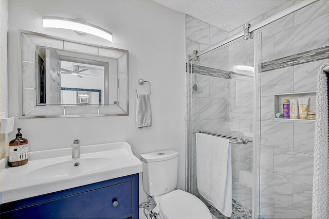 bathroom featuring toilet, vanity, an enclosed shower, a textured ceiling, and ceiling fan