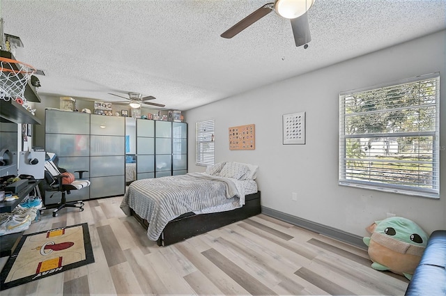 bedroom featuring light hardwood / wood-style floors, a textured ceiling, and ceiling fan