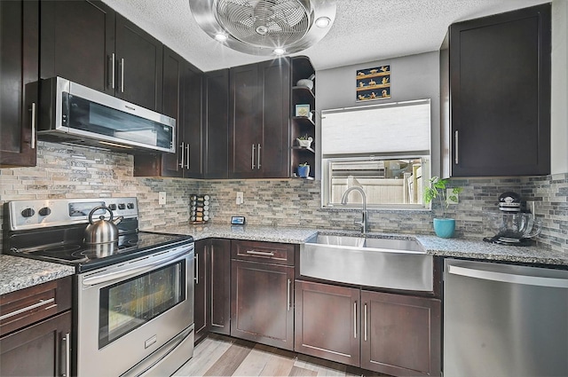 6738 Brentford Rd, Sarasota, FL 34241 - kitchen featuring appliances with stainless steel finishes, a textured ceiling, light wood-type flooring, tasteful backsplash, and light stone counters