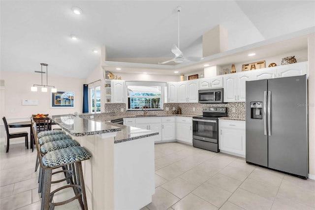 kitchen featuring white cabinets, hanging light fixtures, vaulted ceiling, dark stone countertops, and stainless steel appliances