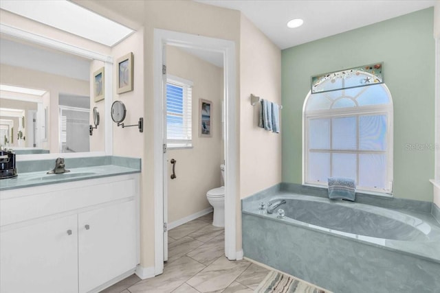 bathroom with vanity, a tub to relax in, toilet, and plenty of natural light