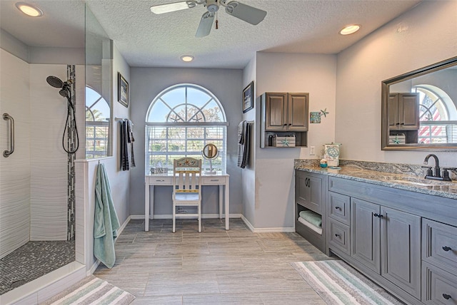 bathroom with vanity, tiled shower, a textured ceiling, and plenty of natural light