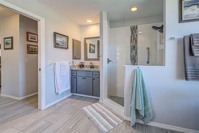 bathroom featuring vanity, a textured ceiling, and tiled shower