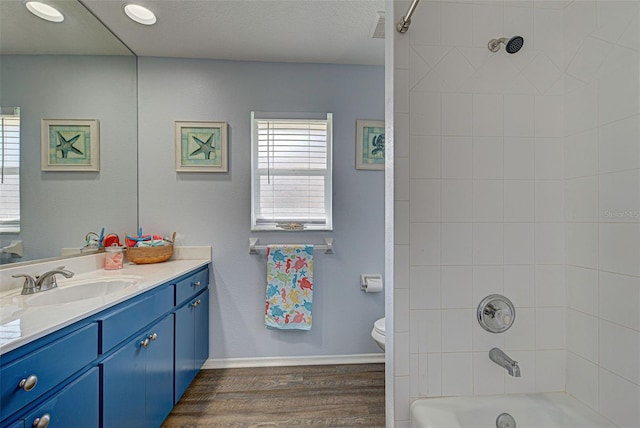 full bathroom featuring vanity, tiled shower / bath, toilet, and wood-type flooring