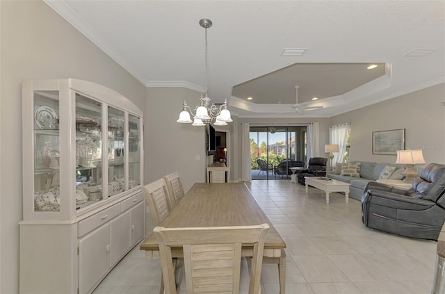 tiled dining area featuring crown molding, a tray ceiling, and ceiling fan with notable chandelier