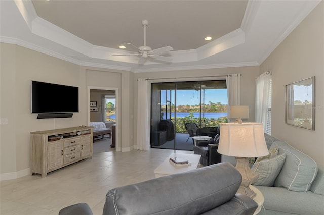 living room featuring ornamental molding, light tile patterned floors, a tray ceiling, and ceiling fan