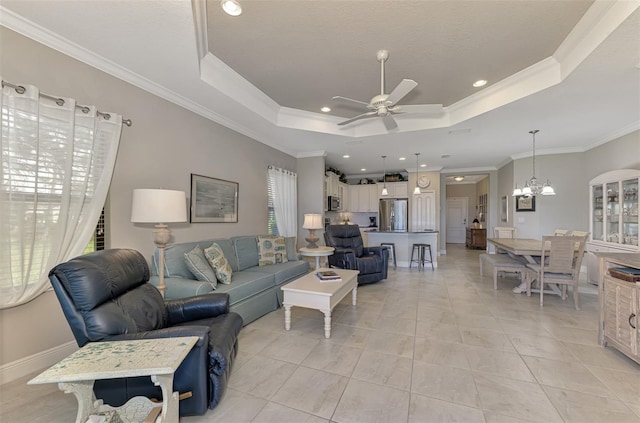 tiled living room with crown molding, a healthy amount of sunlight, ceiling fan with notable chandelier, and a raised ceiling