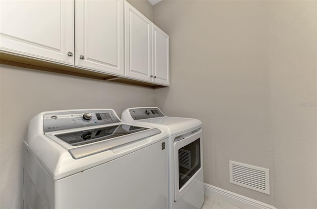 clothes washing area featuring cabinets and washer and clothes dryer