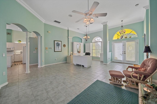 interior space featuring decorative columns, ornamental molding, light tile patterned flooring, a towering ceiling, and french doors