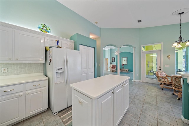 kitchen featuring white fridge with ice dispenser, a kitchen island, white cabinetry, pendant lighting, and a chandelier