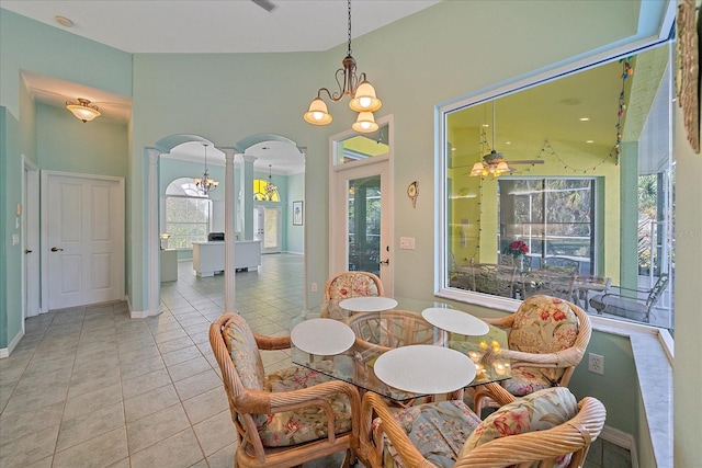 dining area featuring decorative columns, ceiling fan with notable chandelier, a healthy amount of sunlight, and light tile patterned floors