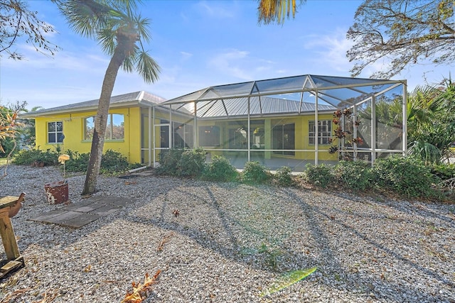 rear view of property featuring a patio and glass enclosure