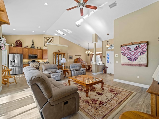 living room featuring light hardwood / wood-style floors, vaulted ceiling, and ceiling fan with notable chandelier