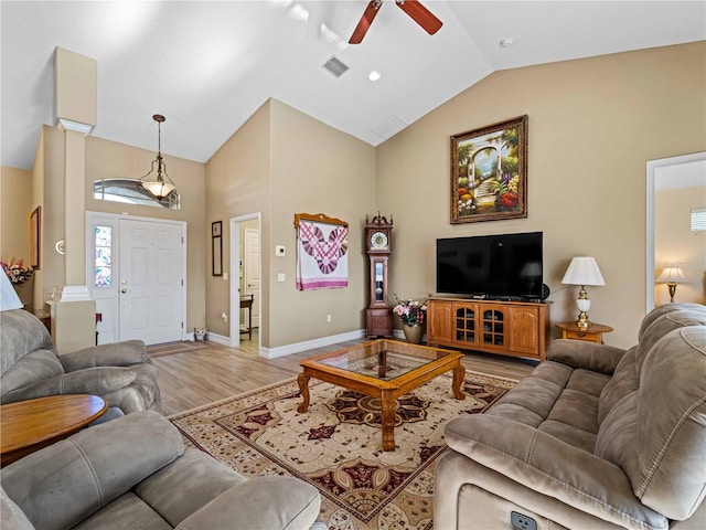 living room featuring decorative columns, lofted ceiling, light wood-type flooring, and ceiling fan