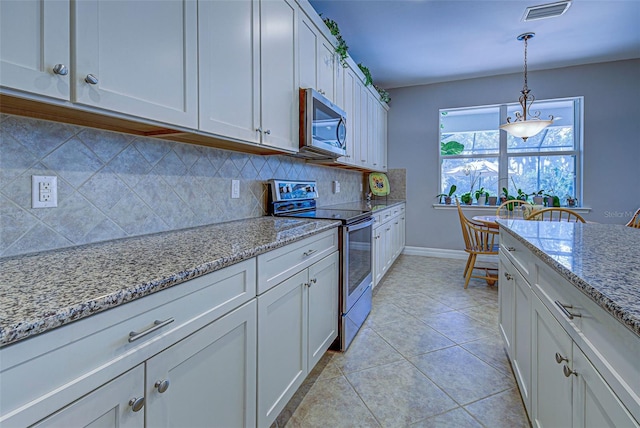 kitchen with light tile patterned flooring, white cabinetry, stainless steel appliances, pendant lighting, and light stone counters