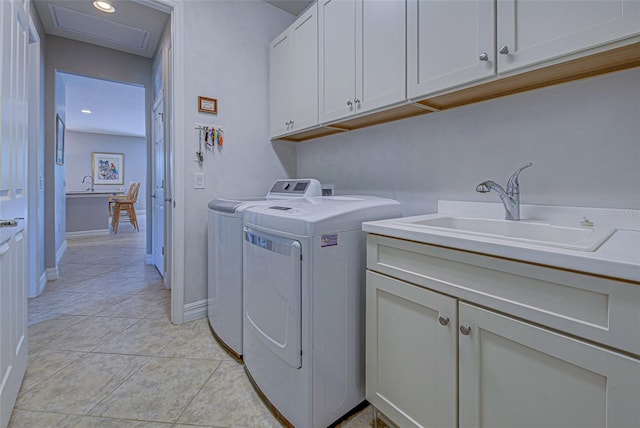 laundry area featuring sink, light tile patterned floors, washing machine and dryer, and cabinets