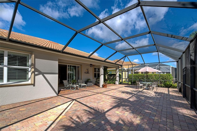 view of patio with ceiling fan and glass enclosure