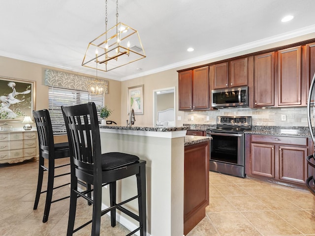 kitchen featuring appliances with stainless steel finishes, a breakfast bar area, hanging light fixtures, ornamental molding, and an inviting chandelier